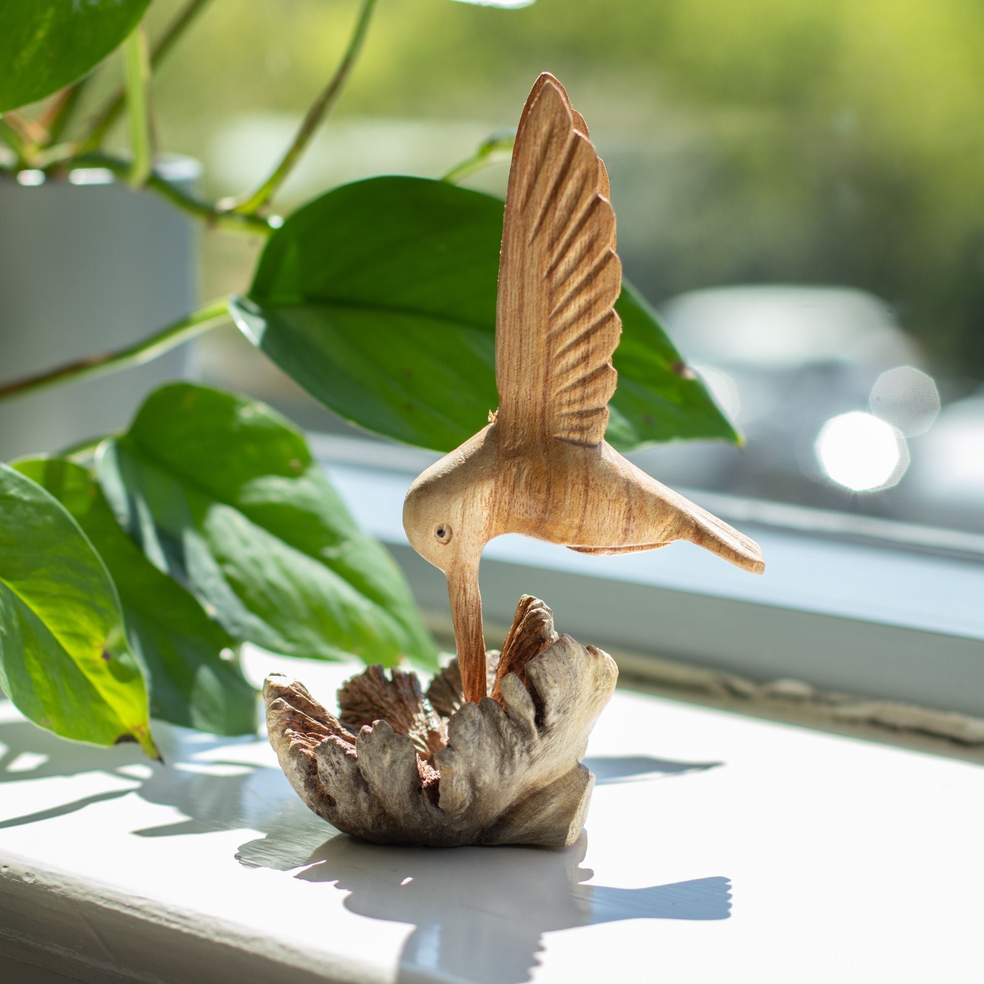 Sculptură realizată manual cu un colibri care bea nectar dintr-o excrescență lemnoasă