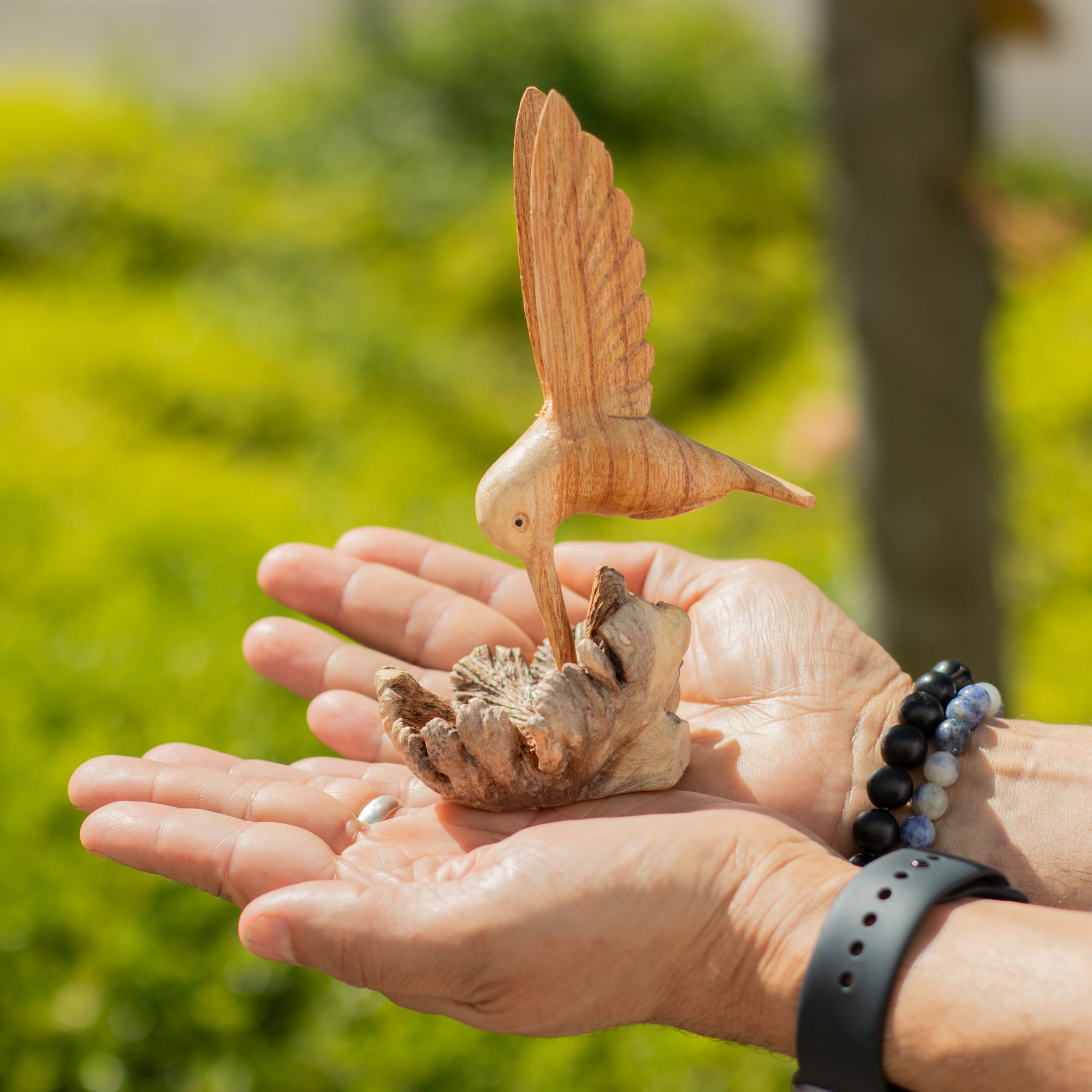 Sculptură realizată manual cu un colibri care bea nectar dintr-o excrescență lemnoasă